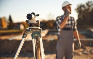 equipamento topográfico em primeiro plano e imagem de um engenheiro ao fundo